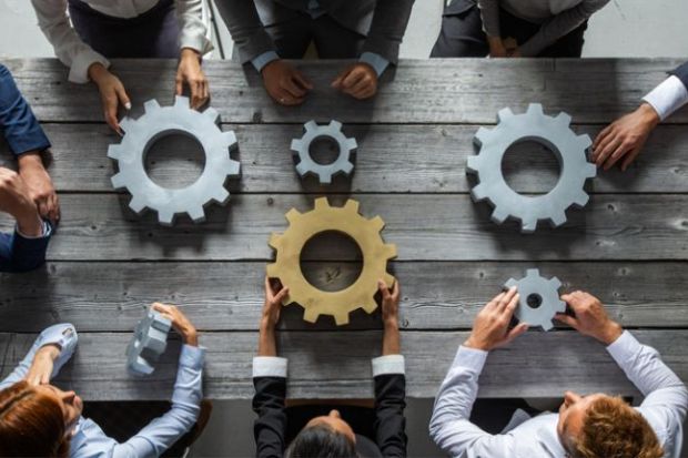 People hold unconnected cogwheels, one of which is gold