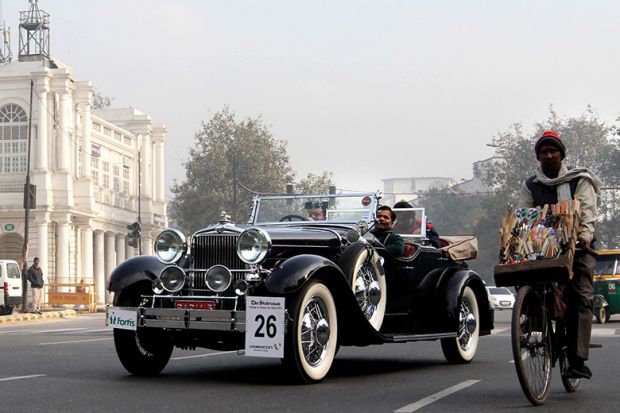 Classic car rally in New Delhi next to person on push bike to illustrate Nepotism warning as Delhi fills thousands of academic posts