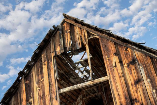 Derelict barn against cloudy blue sky