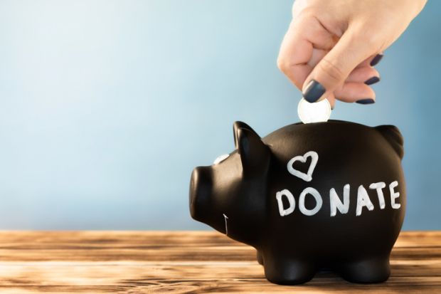 A coin inserted into a piggy bank marked "donations"