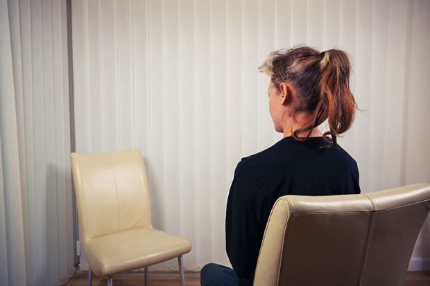 Seated woman looking at empty chair