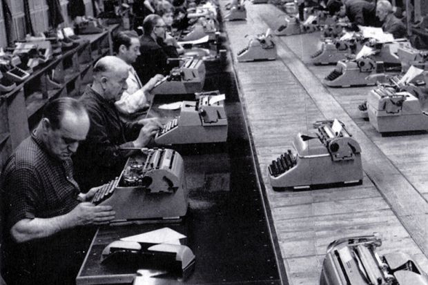 Men typing in a row in a factory