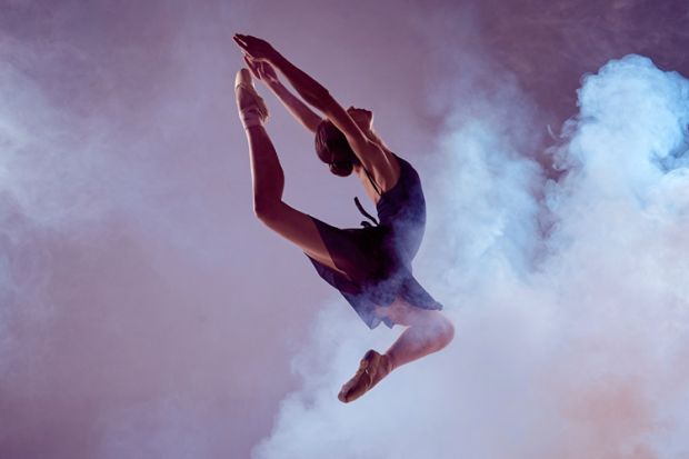 Female ballet dancer jumping through dry ice