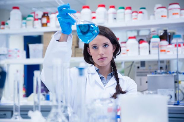 Female scientist examining liquid in flask