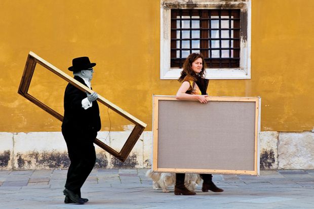 Two people carrying picture frames