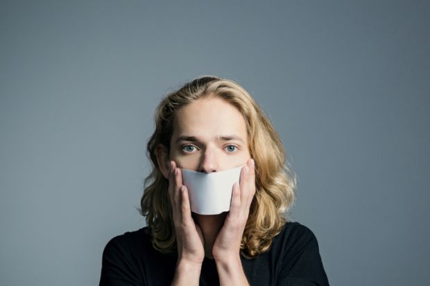 A man holds paper in front of his mouth, symbolising non-disclosure agreements