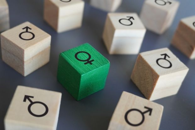 Female symbol surrounded by male symbol on wooden blocks, symbolising gender discrimination