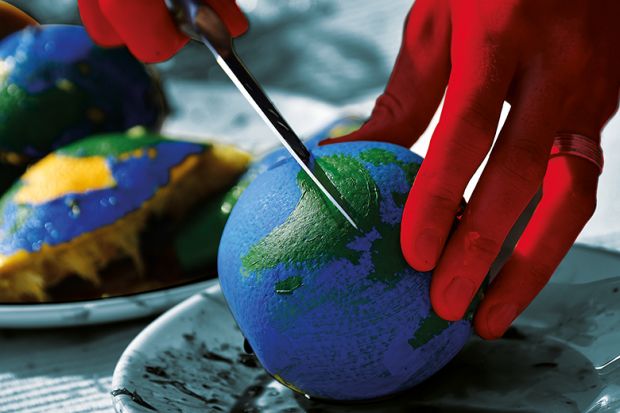 Cutting an orange painted like a globe representing funding cuts