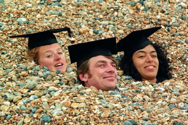 Graduates buried in shingle on Brighton beach, England