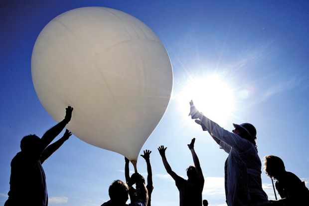 Group of people push balloon into the air