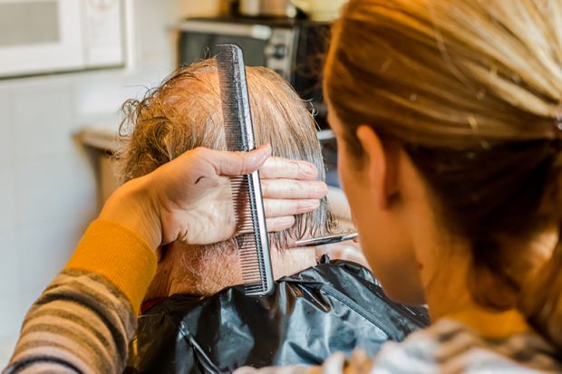 woman give elderly man haircut