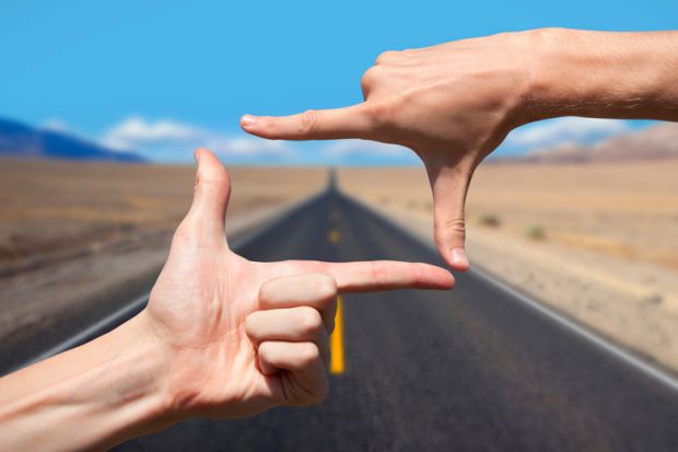 Hands composing photograph of road ahead