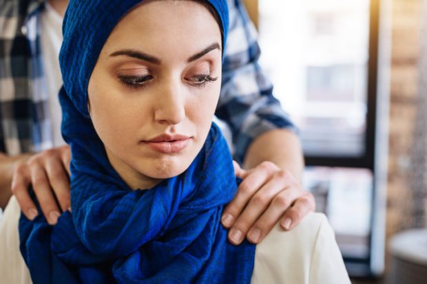 A Muslim woman with male hands on her shoulders, signifying sexual harassment in the Middle East