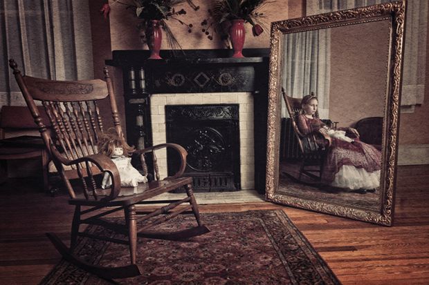 Doll in chair with girl in mirror reflection