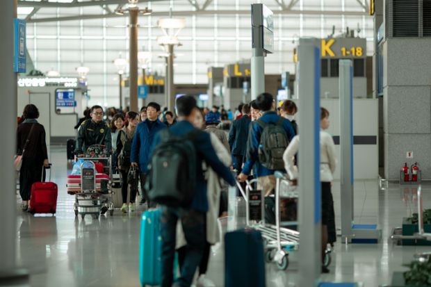 People with suitcases and luggage carts at Incheon International Airport. 