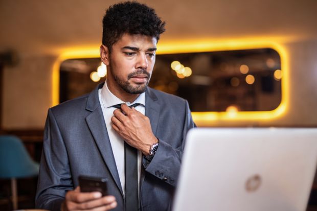 A candidate adjusts his tie before a job interview. Online interviews add an extra layer of difficulty to an already stressful situation.