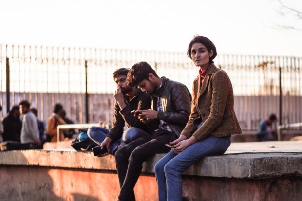 Group of young male and female students sitting inside the university campus of Jamia Millia Islamia entrance door.