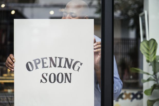 Man putting “store opening” sign in shop window