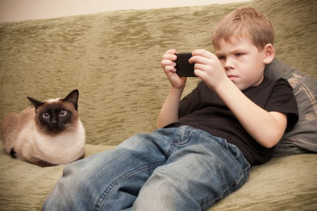 Boy playing Candy Crush on sofa