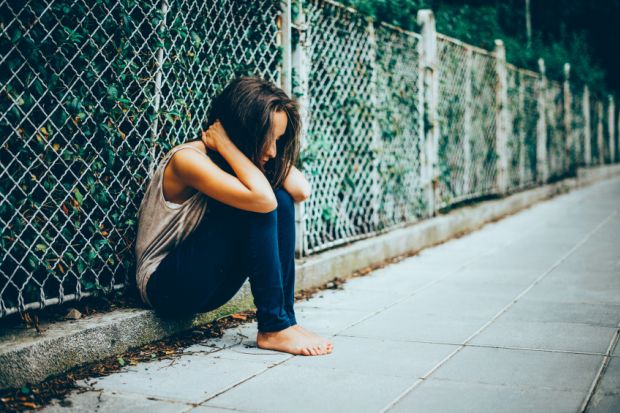 Isolated teenager sitting on street