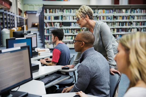 Librarian helping student at computer in library