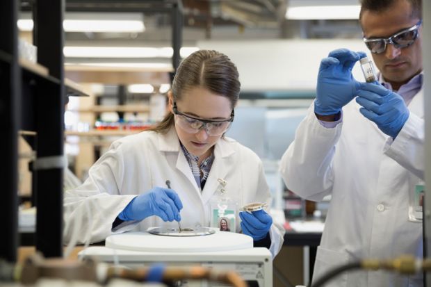 Scientists using centrifuge in laboratory