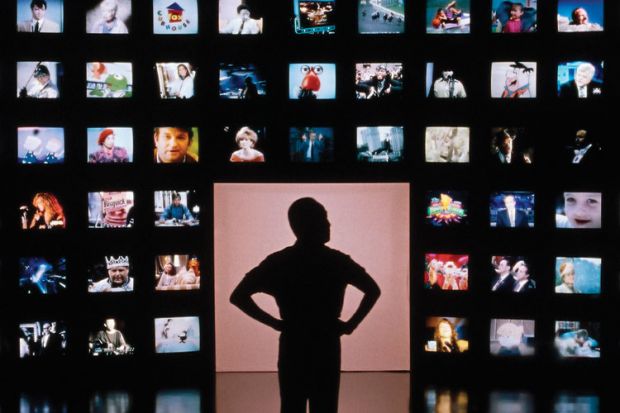 Male silhouette facing wall of television screens