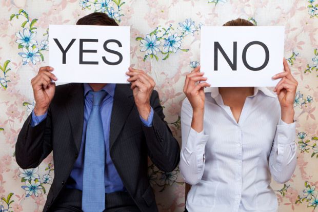 Man and woman holding yes/no cards in front of faces