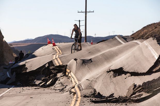 Man cycles along severely damaged road