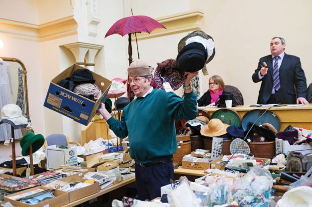 Man holding collection of hats at auction