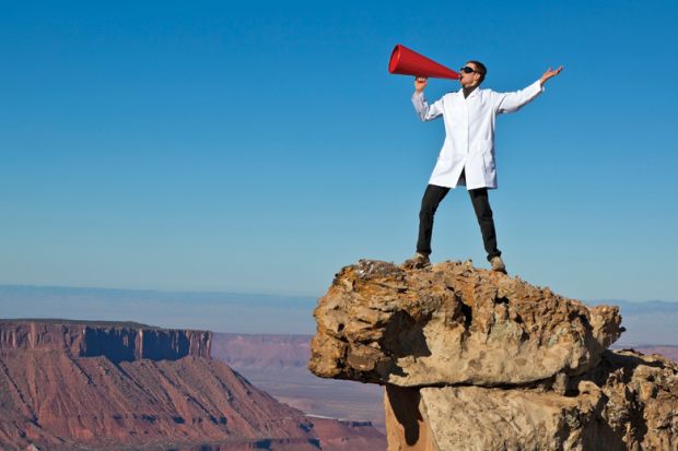 Man in lab coat shouting from rock with megaphone