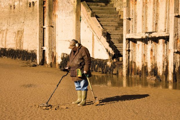 Man metal detecting on beach