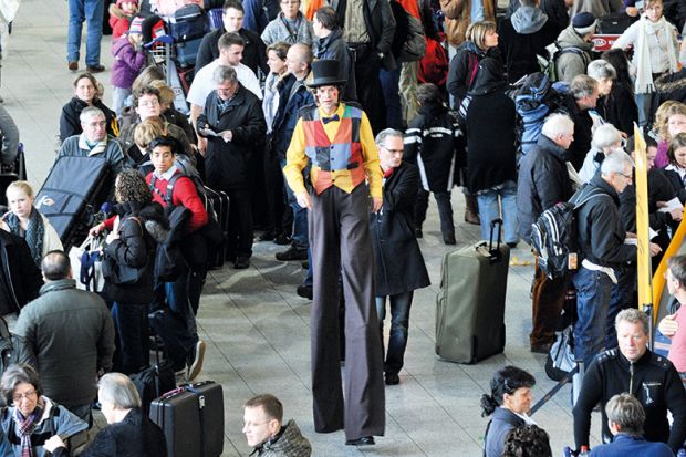 Man on stilts walking through crowd