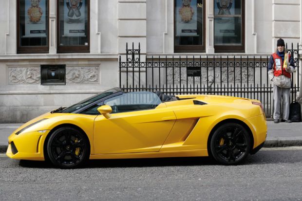 Man selling Big Issue next to Lamborghini, Covent Garden, London