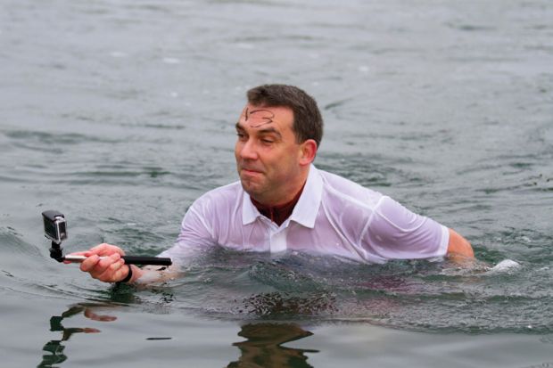 Man standing in water taking selfie photograph