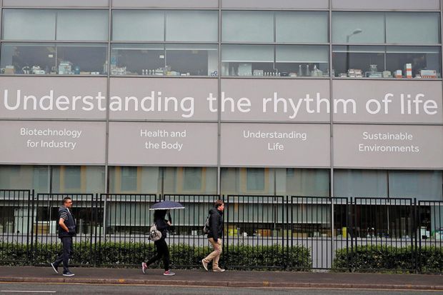 People walk past a science building at the University of Manchester, England