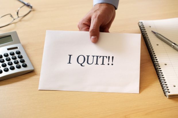 Man's hand holding 'I quit' resignation note