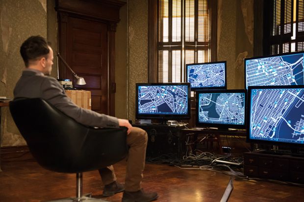 A man sitting in front of a bank of computer screens