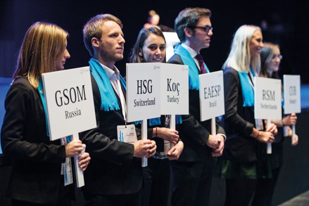 Master's degree students holding university name paddles