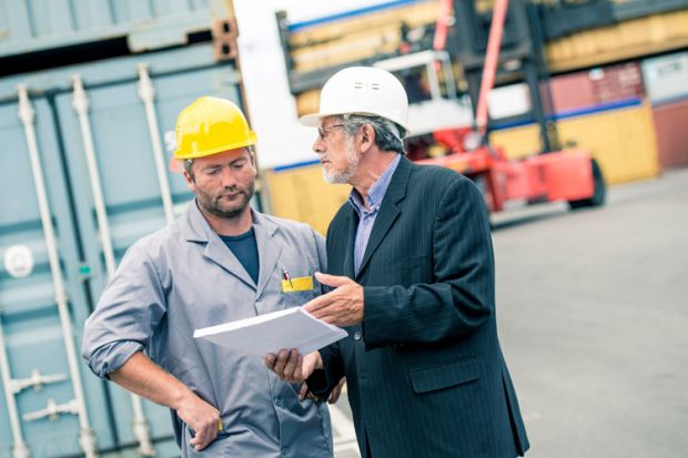 Men discussing paperwork on ship dock