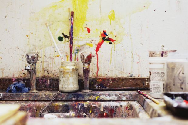 Paint and paintbrushes beside artist's kitchen sink