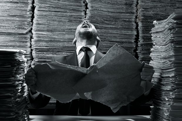 A man laughing amid a pile of paperwork