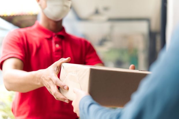 A shopworker hands over a brown parcel to a customer