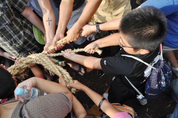 People pulling rope during tug of war festival