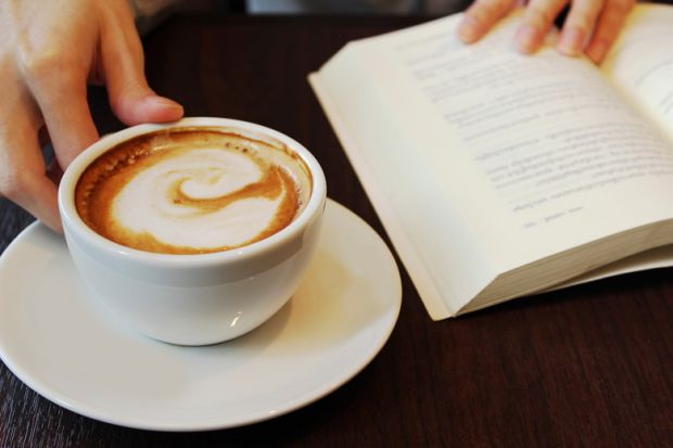 Person reading and drinking coffee