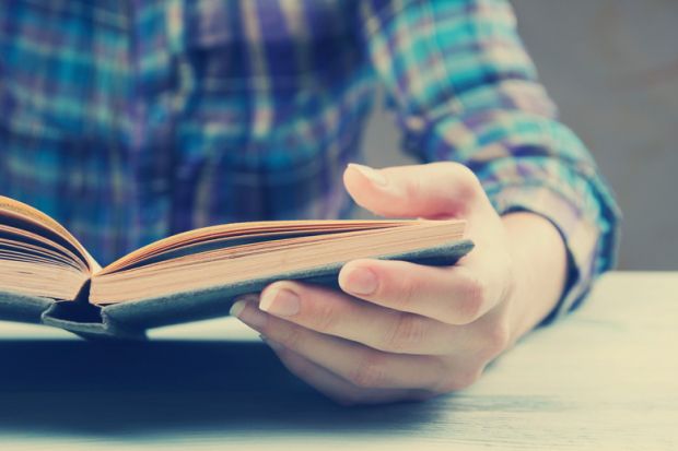 Person sat reading book at table