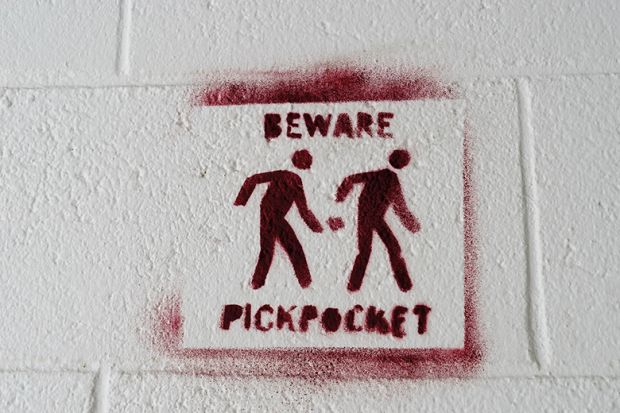 Pickpocket warning sign stencilled on to a white wall to. illustrate I’m being docked pay for boycotting marking – but I teach for free!