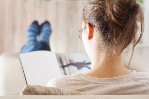 A woman reading a book with her feet up