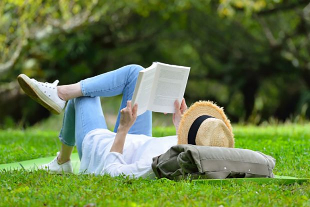 A woman lying on her back reading