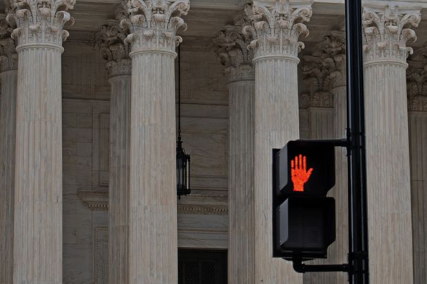 Red hand stop sign in from of classical columns to illustrate that serious abuses should stop being investigated only by universities.